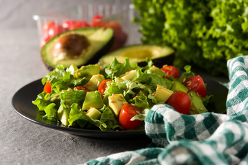 Salad with avocado, lettuce, tomato and flax seeds on gray background	