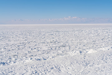 Fototapeta na wymiar Snow covered frozen ice lake located in Xinjiang China Sayram lake. Winter season.