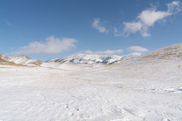 Fototapeta na wymiar Snow mountain and snow field grassland near by the Xinjiang China Sayram lake. Winter season.