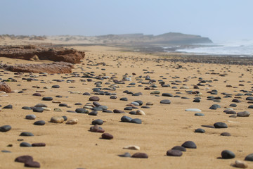 Fototapeta na wymiar Pebbles on a sandy beach by the ocean
