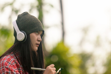 asian female teenagers wear gray hats, pen holders, and notebooks. Listen to music with white...