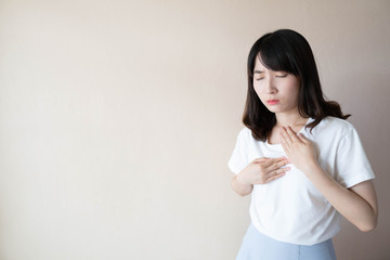 Acid reflux or Gastroesophageal reflux disease (GERD) concept. Young asian female suffering from heartburn or chest discomfort symptoms over white background. Health care and medical concept.