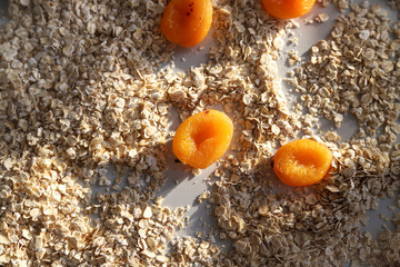 Fototapeta na wymiar Healthy breakfast concept – oat flakes and dried apricot at sunny day. Food for heart health and energy. Creative granola or muesli ingredients