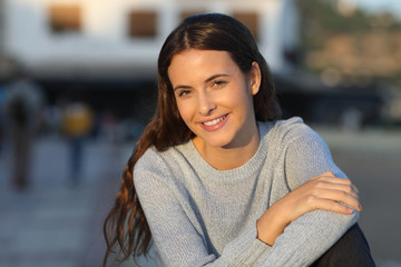 Happy teenage girl sitting looking at camera in the street