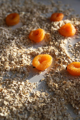 Healthy breakfast concept – oat flakes and dried apricot at sunny day. Food for heart health and energy. Creative granola or muesli ingredients