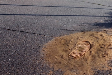 handful of sand on the pavement with a boot mark