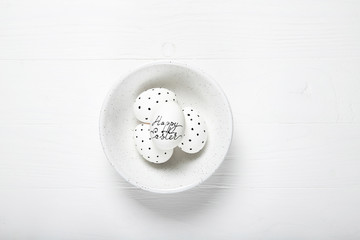 Plate with easter eggs on a white wooden background
