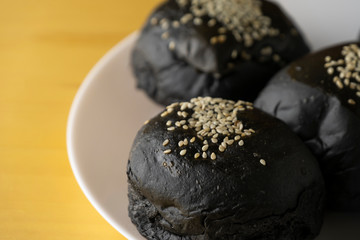Loaf of charcoal bread bun with white sesame on top in the white plate