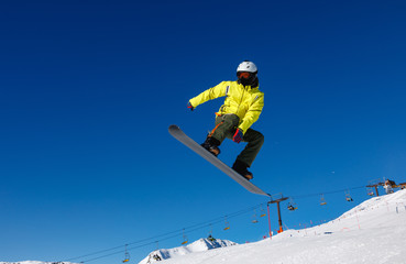 Naklejka na ściany i meble Bright color snowboarder jumps on blue sky backdrop