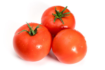 three fresh tomatoes with green leaves isolated on white background