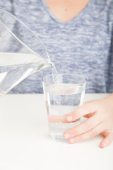 Pouring jug of water into glass of water