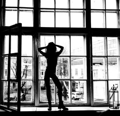 Fototapeta na wymiar silhouette fashion girl in black leather jacket in window