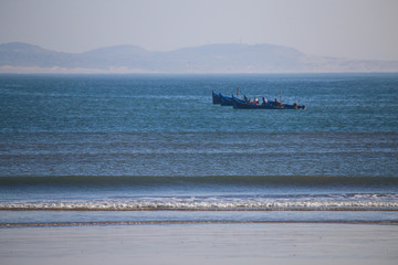 Perfect wave on the background of fishing boats