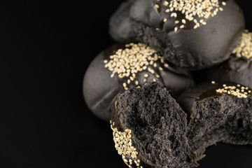 Loaf of charcoal bread bun with white sesame on top isolated on black background