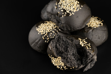 Loaf of charcoal bread bun with white sesame on top isolated on black background