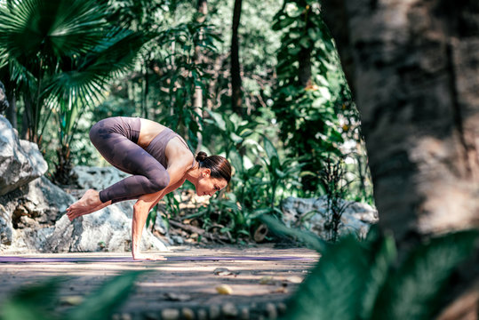 Cultivate a healthy body. Full-length shot of caucasian woman standing in Crow pose, Bakasana while practicing yoga outdoors, in a garden. Healthy lifestyle and relaxation concept
