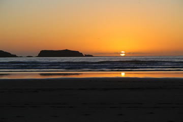 Wet sand at low tide on a sunset background