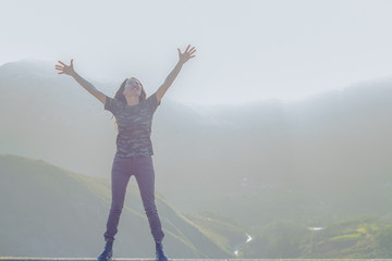 Fototapeta na wymiar Happy young woman in nature with arms raised