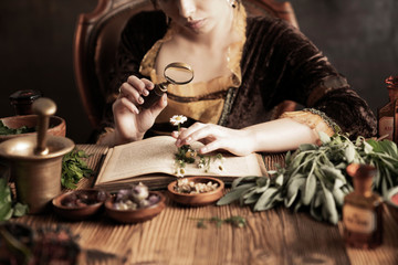 Natural medicine concept. Vintage pharmacist preparing natural medicament. Brass mortar and  bottles. Rustic table. Assorted dry herbs in bowls. © zolnierek