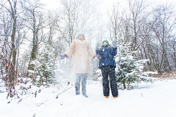 Fototapeta na wymiar Parenting, fun and season concept - Happy mother and son having fun and playing with snow in winter forest