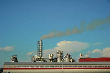 Smoke from the chimney of a wood processing plant rises into the sky polluting the environment.