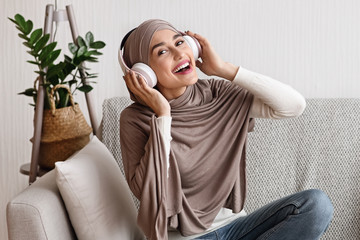 Portrait of happy muslim girl in hijab and wireless headphones