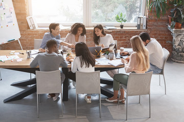 Obraz na płótnie Canvas Friendly business team sitting around table, having meeting