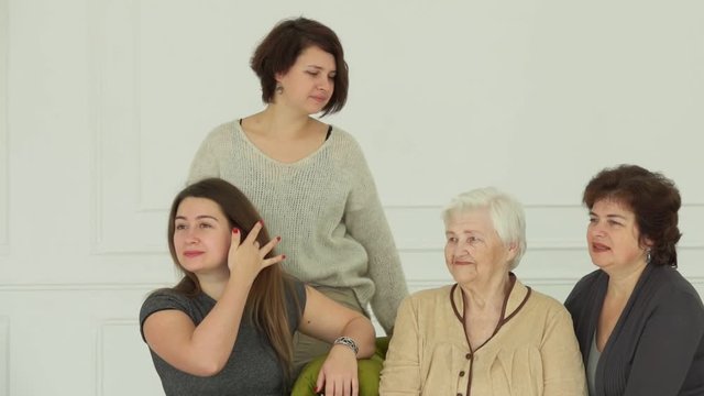Photographer is taking pictures of an elderly white-haired woman with her granddaughters. Beautiful multi-generations family enjoys togetherness 