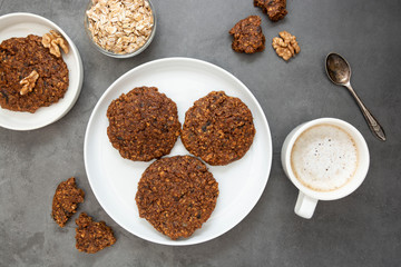 Healthy homemade cookie with oat flakes, dried fruits and seeds. Top view, flat lay biscuits over dark background with copy space.