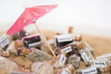 Glass test-tube with sand of different summer vacation destinations. Vacation time abstract photo.