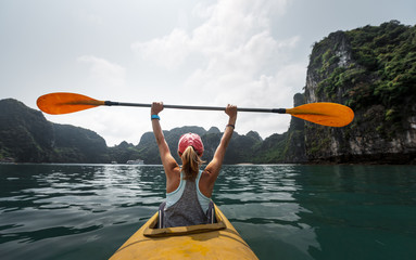 Woman paddles kayak in the Ha Long Bay in Vietnam