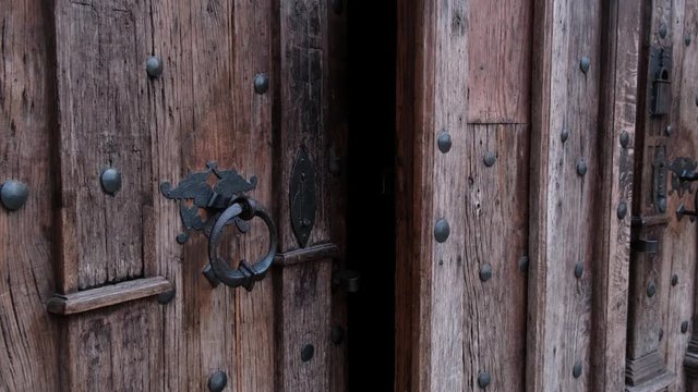 Close-up of closing old wooden door with metal handle in ancient medieval Catholic church. For religion, histotic, architecture background.