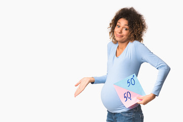 Baby's gender. African-american pregnant woman holding pink and blue card