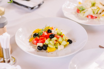 Vegatarian salad of fresh vegetables. Delicious vegetables in a fresh salad with black olives and pieces of cheese.