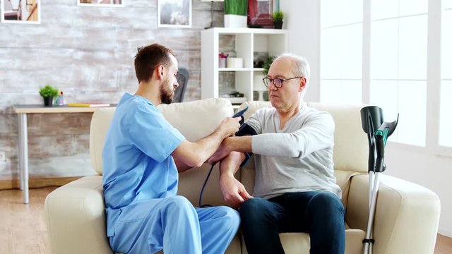 Male nurse measuring blood pressure of a man pensioner