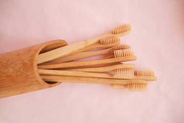 wooden bamboo toothbrushes on white and pink background