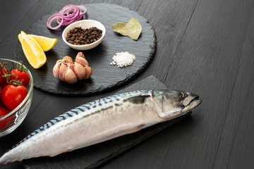 Fresh, raw mackerel with spices on a black concrete background