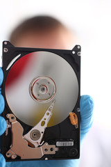 A male repairman wearing blue gloves is holding a hard drive from computer or laptop in hands....