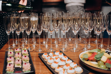 the girl pours champagne into glasses on the buffet table