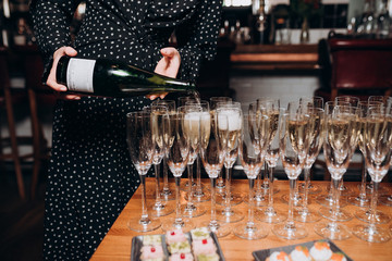 the girl pours champagne into glasses on the buffet table