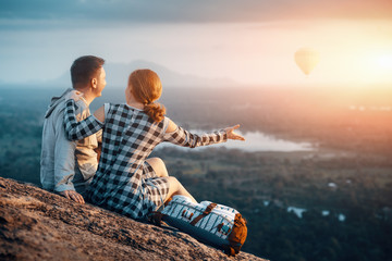 Happy couple enjoying the company of each other during a beautiful sunset sitting on Pidurangala...