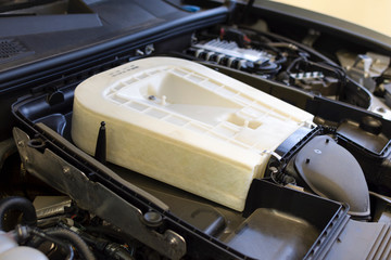 Engine air filter of a modern car. Close-up air filter mounted on a car against the background of the engine compartment. Technical photo.