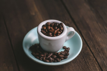 cup with coffee grains on a wooden background.