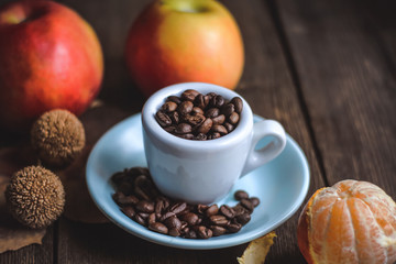 cup with coffee grains and fruits on a wooden background..
