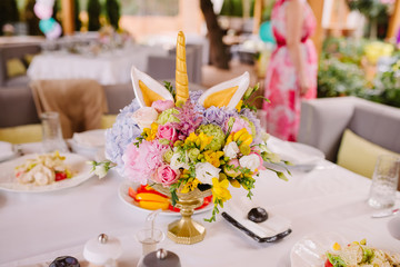Festive food on the table at the restaurant. Stylish decoration of the table with flowers in a vase and a candle. Unicorn theme