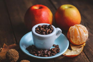 cup with coffee grains and fruits on a wooden background..