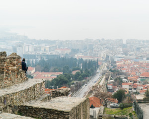 the view from the walls of thessaloniki a man is sitting on the edge and enjoy the peaceful moment