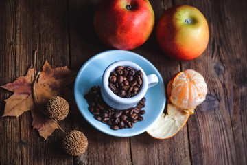 cup with coffee grains and fruits on a wooden background..