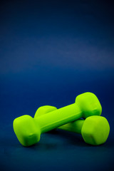 Green dumbbells lie on top of each other on a blue background
