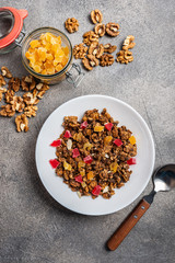Granola with dried fruits in a white plate on a gray background. Top view. Close-up.